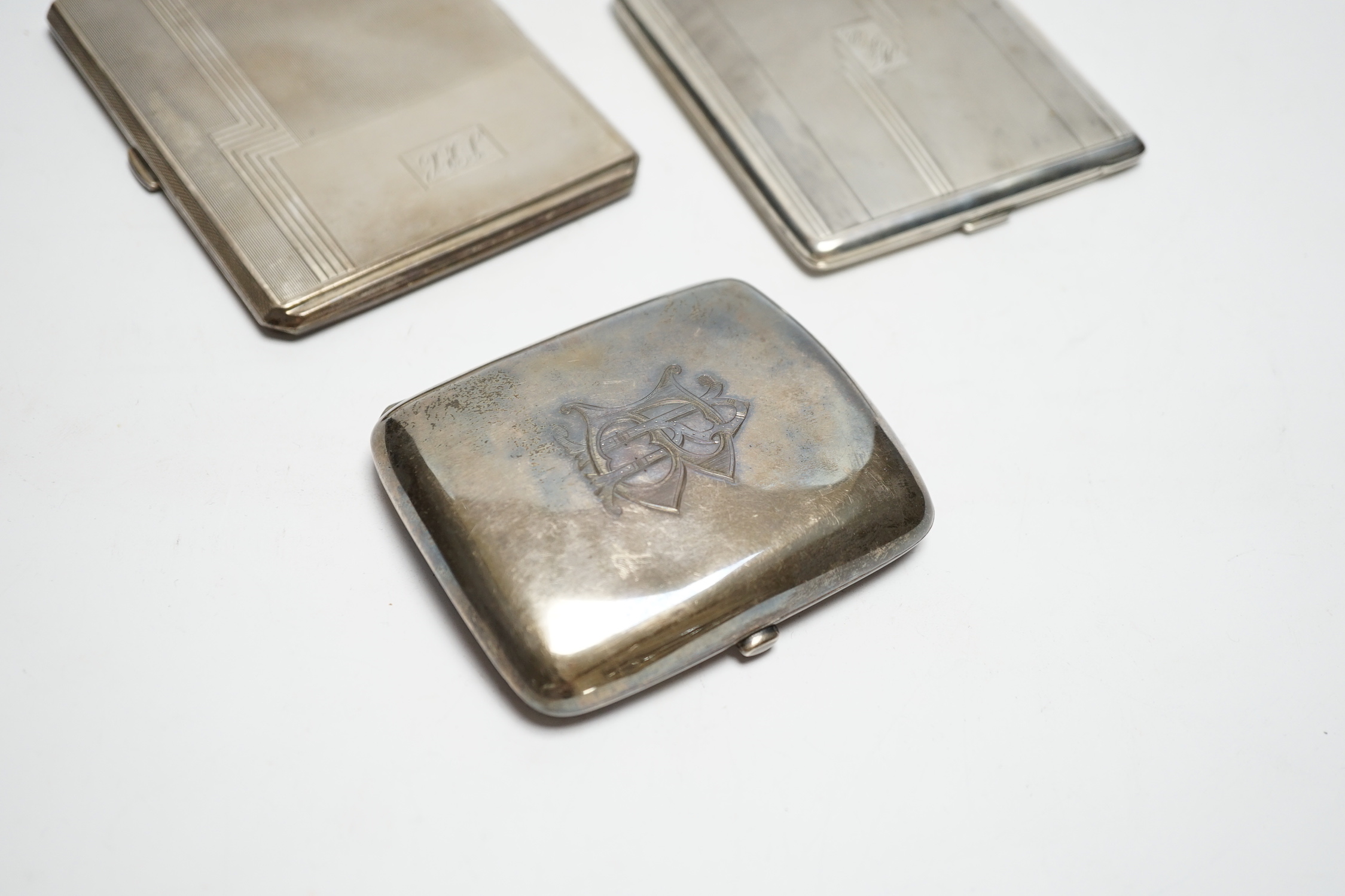 Three silver cigarette cases, including two Art Deco, largest 11.4cm.